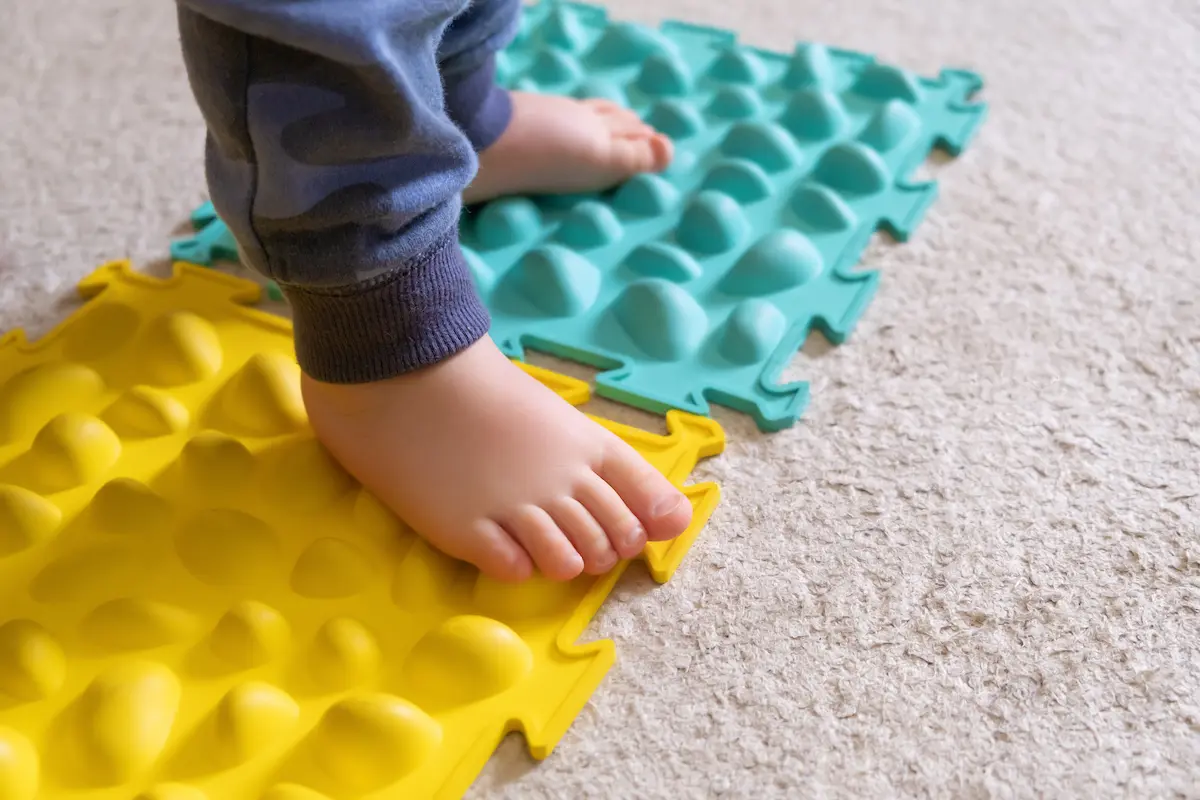 Imagen de un niño pequeño interactuando con una terapeuta mediante juegos o actividades de estimulación temprana en un entorno cálido.
