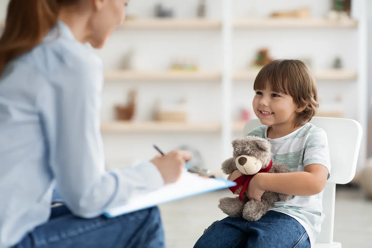 Niño realizando una actividad guiada con una profesional, utilizando materiales didácticos o juegos para estimular habilidades cognitivas o sociales.